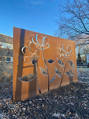 Panneau décoratif floral en acier Corten installé dans un jardin au Maroc, idéal pour la décoration extérieure et l'aménagement paysager.