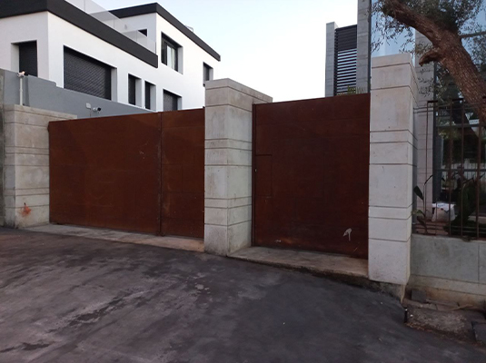 Portail en acier Corten Maroc installé entre des piliers en béton à l’entrée d’une villa contemporaine