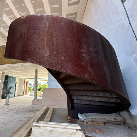 L’acier Corten utilisé pour l’habillage courbe d’un escalier colimaçon sur mesure dans une construction contemporaine