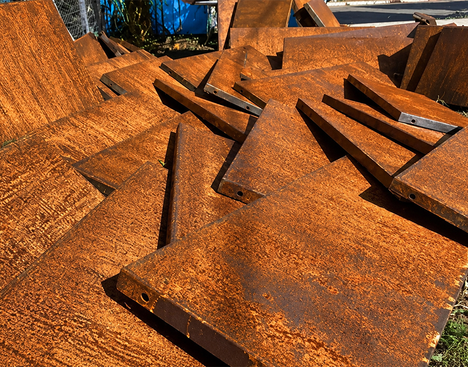 Atelier de fabrication acier Corten avec pièces métalliques découpées présentant une patine brun orangé avant assemblage contactez nous pour domander votre devis acier Corten