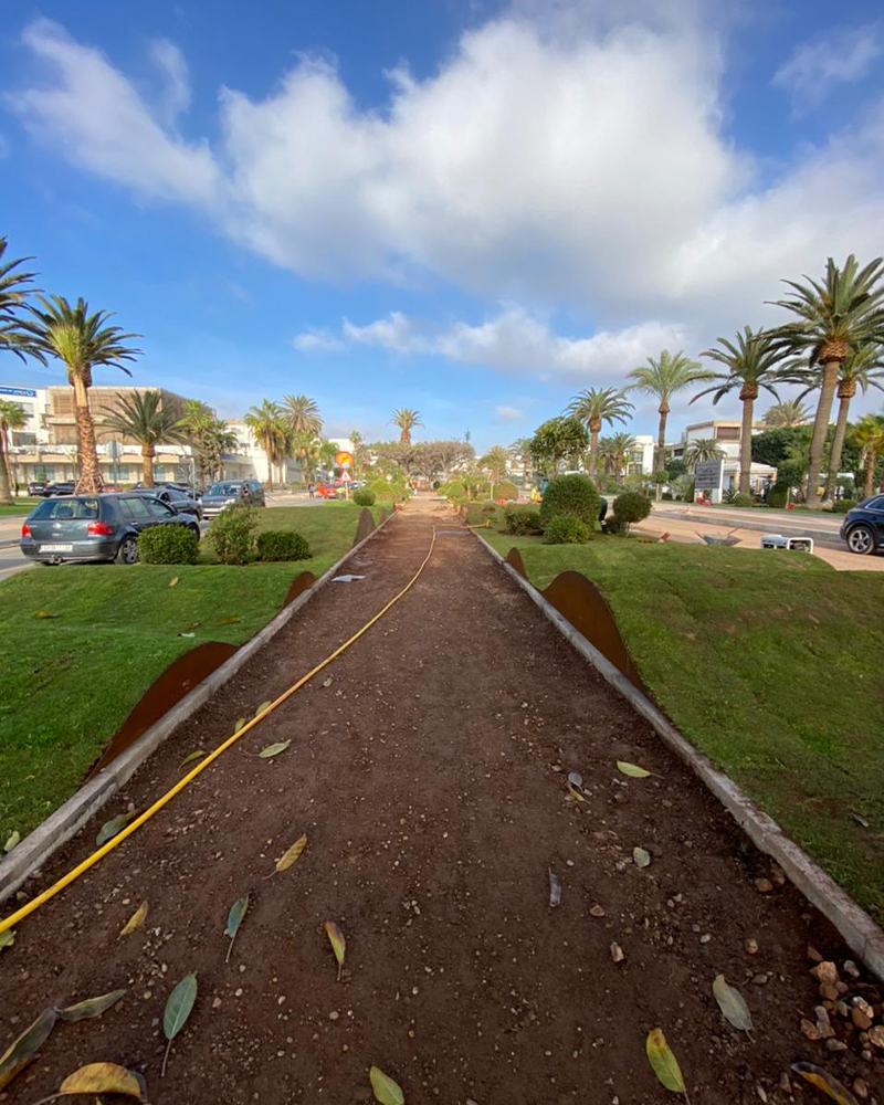 Bordures en acier Corten Maroc installées le long d’un chemin paysager dans un espace urbain bordé de palmiers