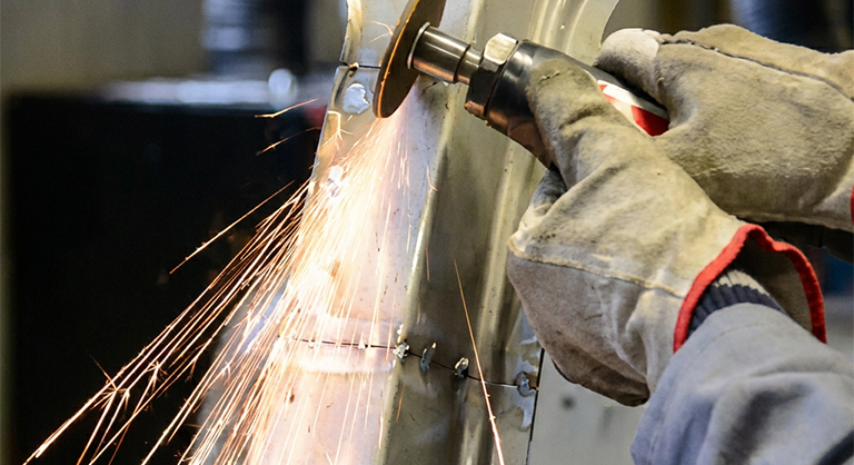 Fabrication acier Corten avec meulage de précision sur une pièce métallique dans un atelier spécialisé