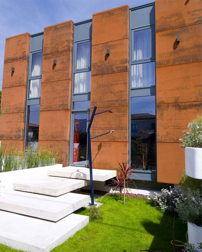 Projets en acier Corten avec panneaux verticaux patinés installés sur la façade vitrée d’un bâtiment contemporain