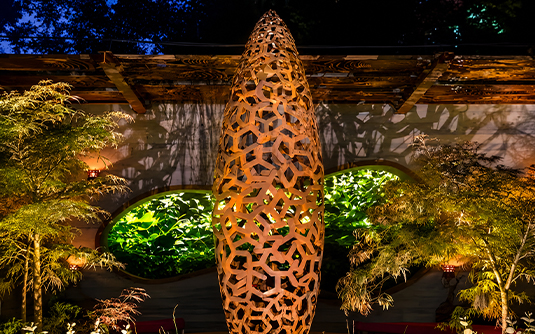 Projets en acier Corten avec sculpture verticale ajourée et éclairage décoratif dans un jardin contemporain